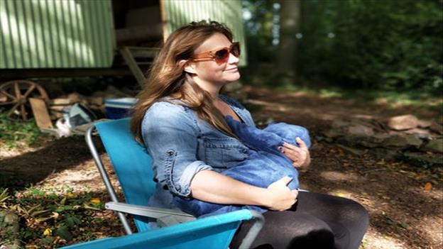 woman breast feeding baby while sitting on chair